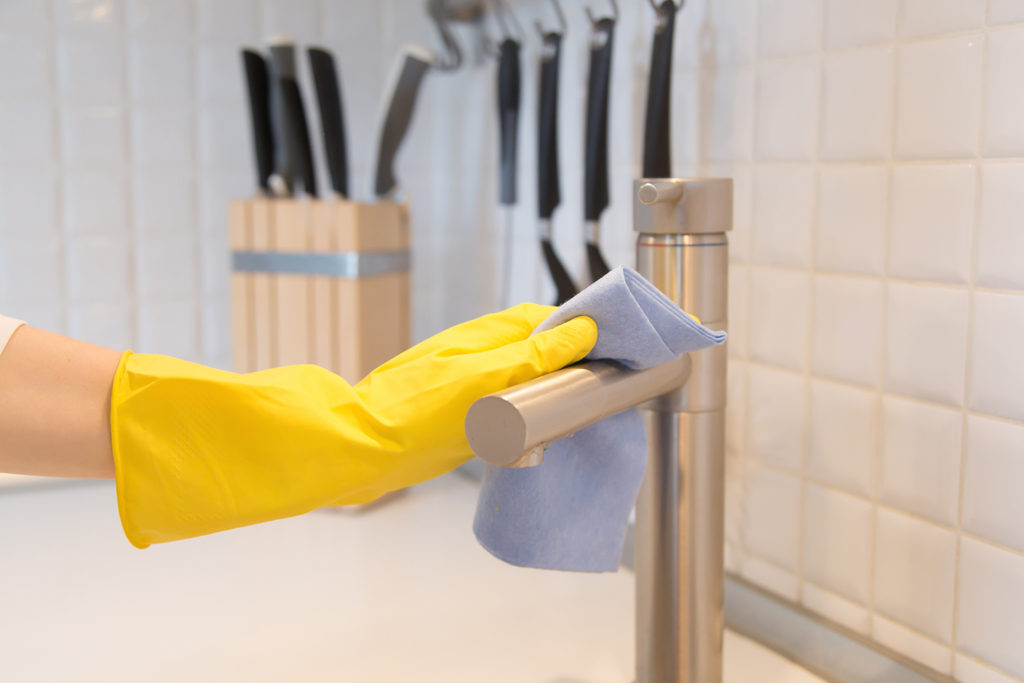 closeup female hand gloves cleaning kitchen tap